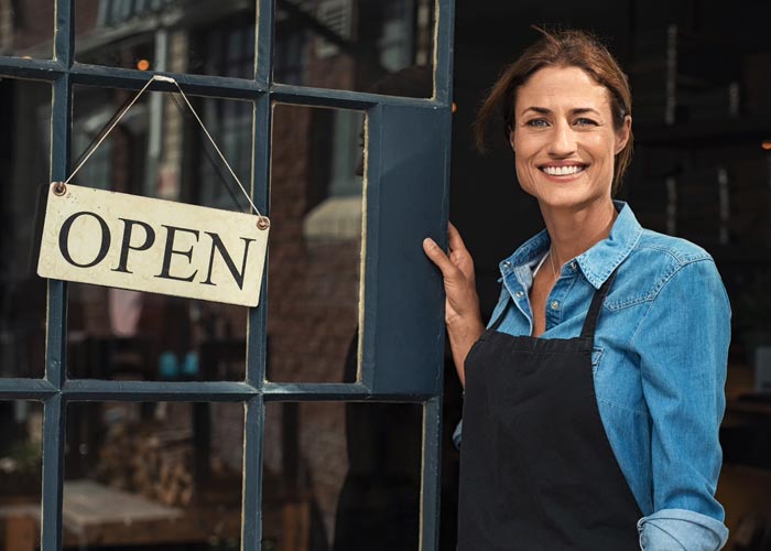 Woman standing in a business doorway next to an Open sign