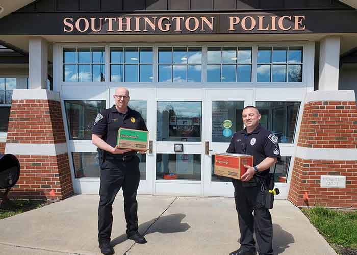 Police officers holding boxes of girl scout cookies