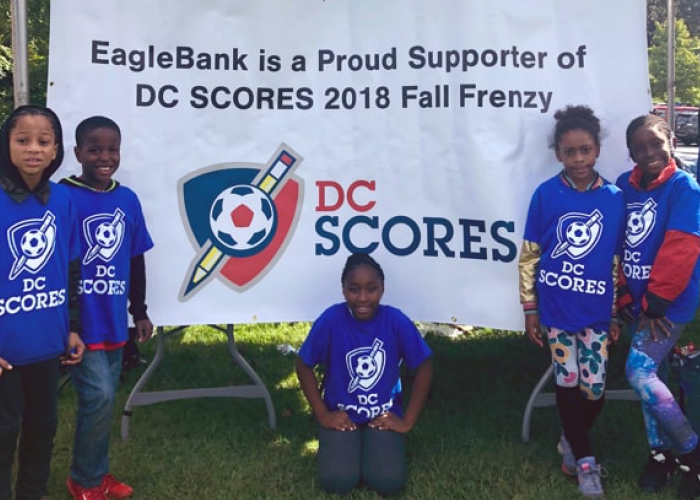 A youth soccer team poses in front of an Eagle Bank sponsorship banner