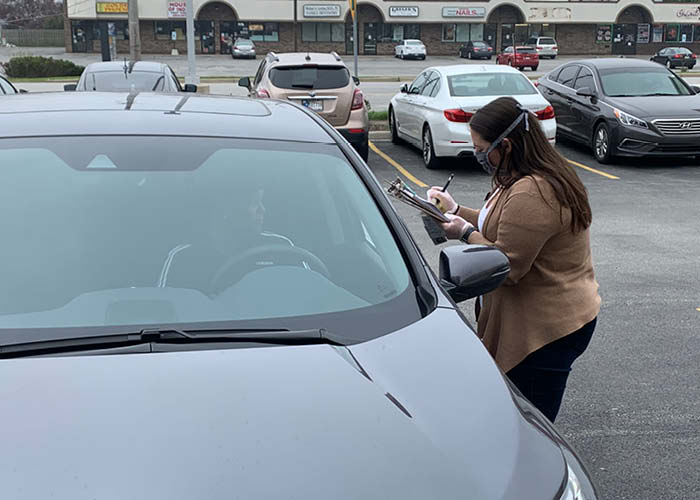 A bank employee brings loan paperwork to a customer in his car