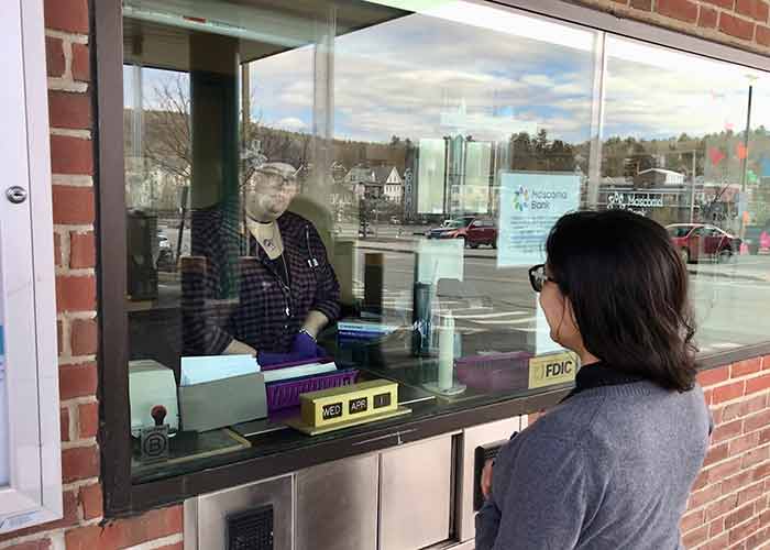 A bank customer walks up to a teller window