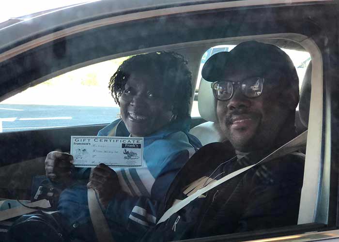 Drive-thru customers hold up a gift card