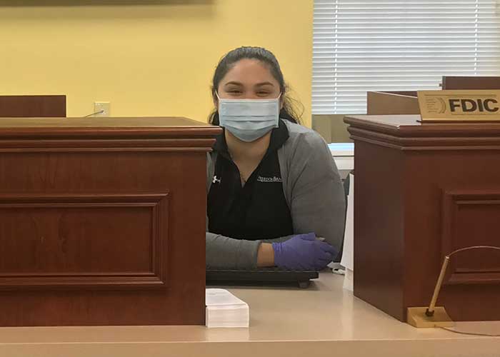 A bank teller wearing a mask and gloves